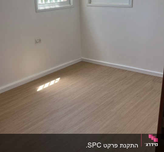 חדר עם רצפת פרקט חדשה ושני חלונות